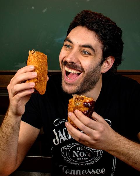 Cliente sorridente dello Shameless Pub mentre morde una frittatina fritta