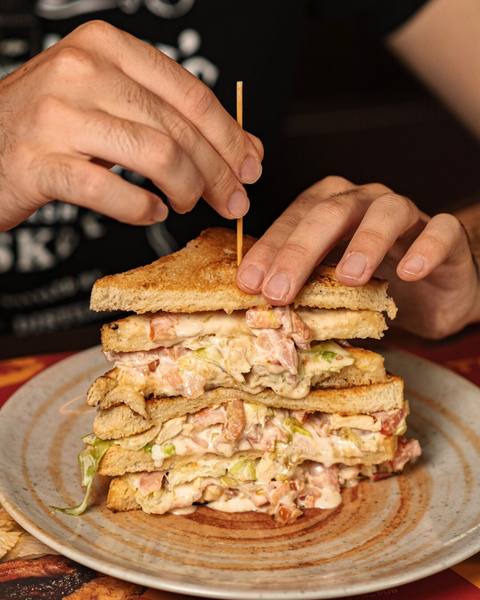 Club sandwich a tre strati con pollo e bacon servito allo Shameless Pub