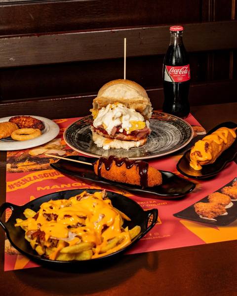 Hamburger con contorno di patatine, cheddar e bacon su tavolo dello Shameless Pub