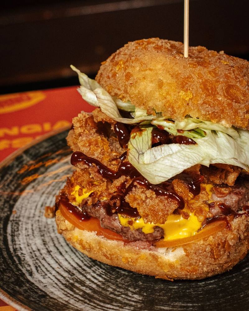 Panino fritto dello Shameless Pub con crispy chicken, bacon e salsa barbecue su piatto in ceramica