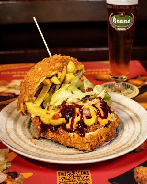 Panino fritto con anelli di cipolla e salse accompagnato da una birra alla spina