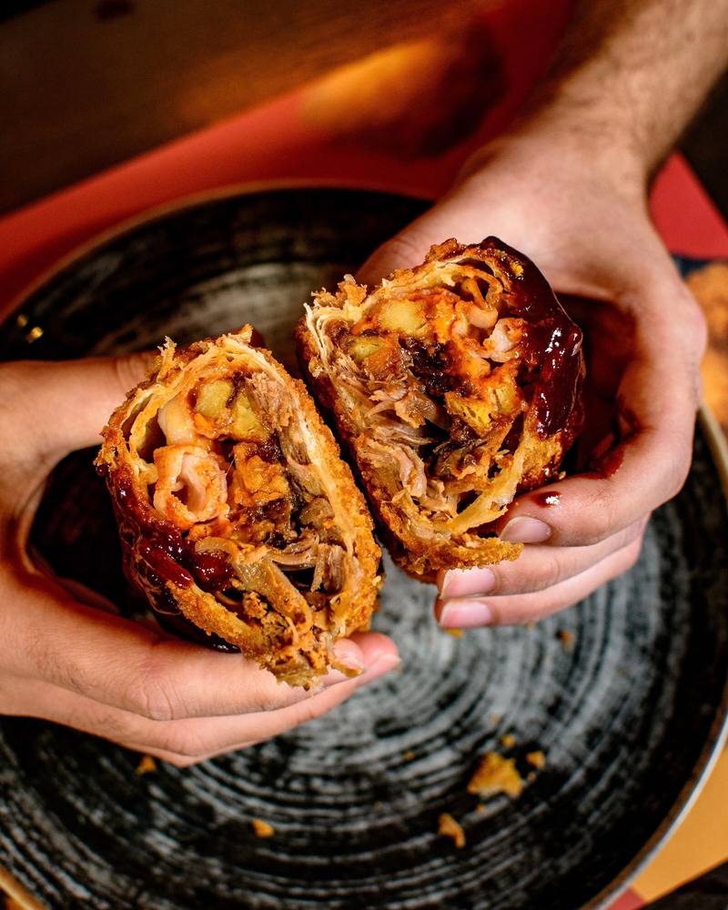 Wrap fritta con pulled pork dello Shameless Pub tagliata a metà e tenuta in mano